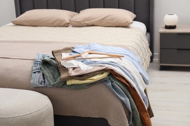 Photo of Pile of different clothes on bed at home