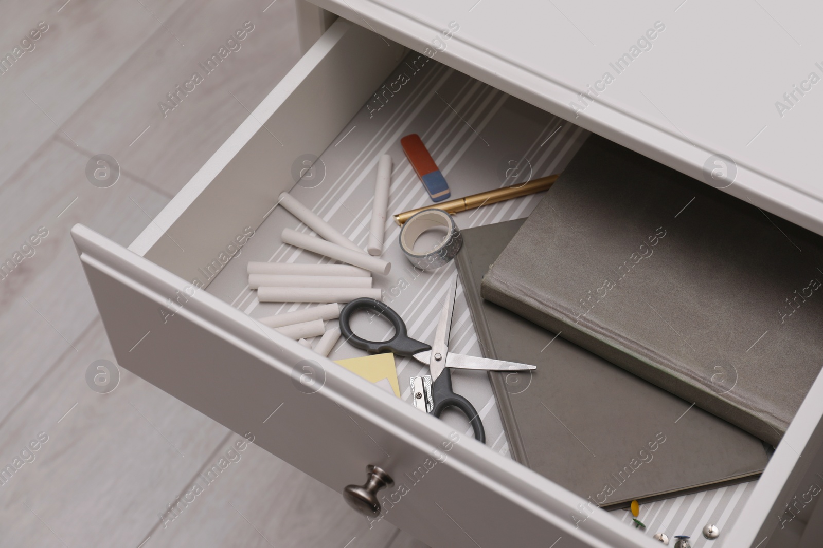 Photo of Office supplies in open desk drawer, above view