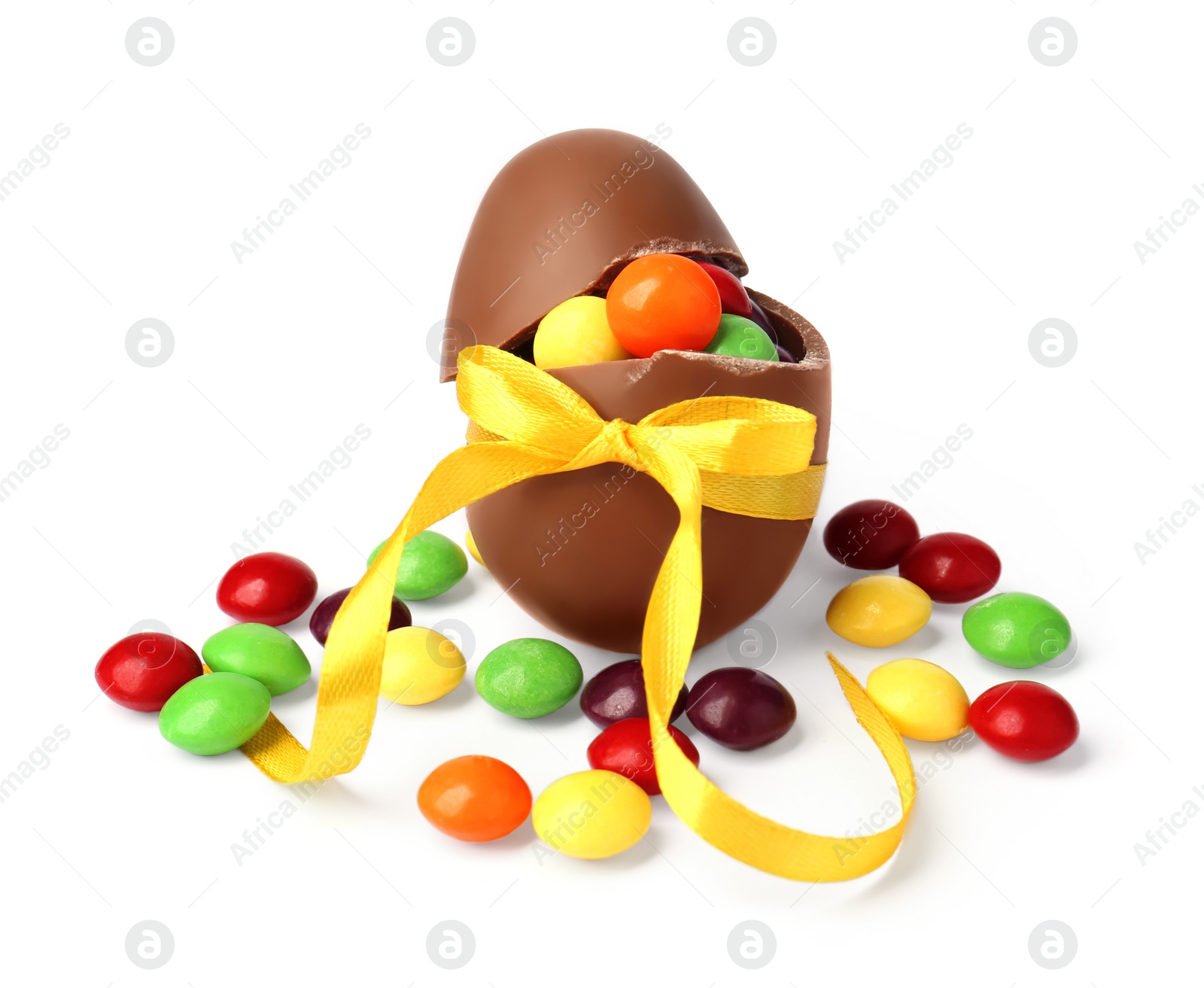 Photo of Tasty chocolate egg with yellow bow and colorful candies isolated on white