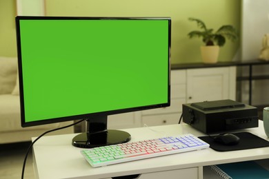 Photo of Modern computer and RGB keyboard on white table indoors. Mockup green screen