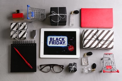 Photo of Flat lay composition with tablet and gift boxes on grey table. Black Friday Sale online