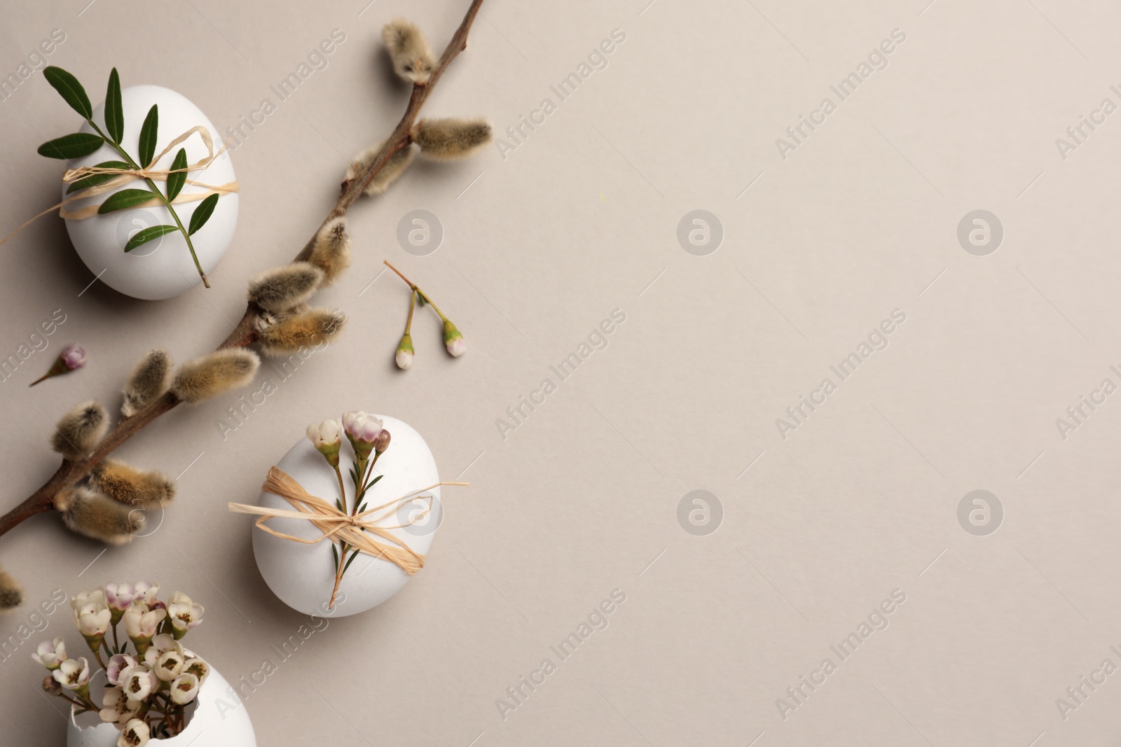 Photo of Flat lay composition with chicken eggs and floral decor on light grey background, space for text. Happy Easter