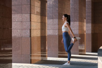 Photo of Beautiful woman in stylish sportswear stretching outdoors, space for text