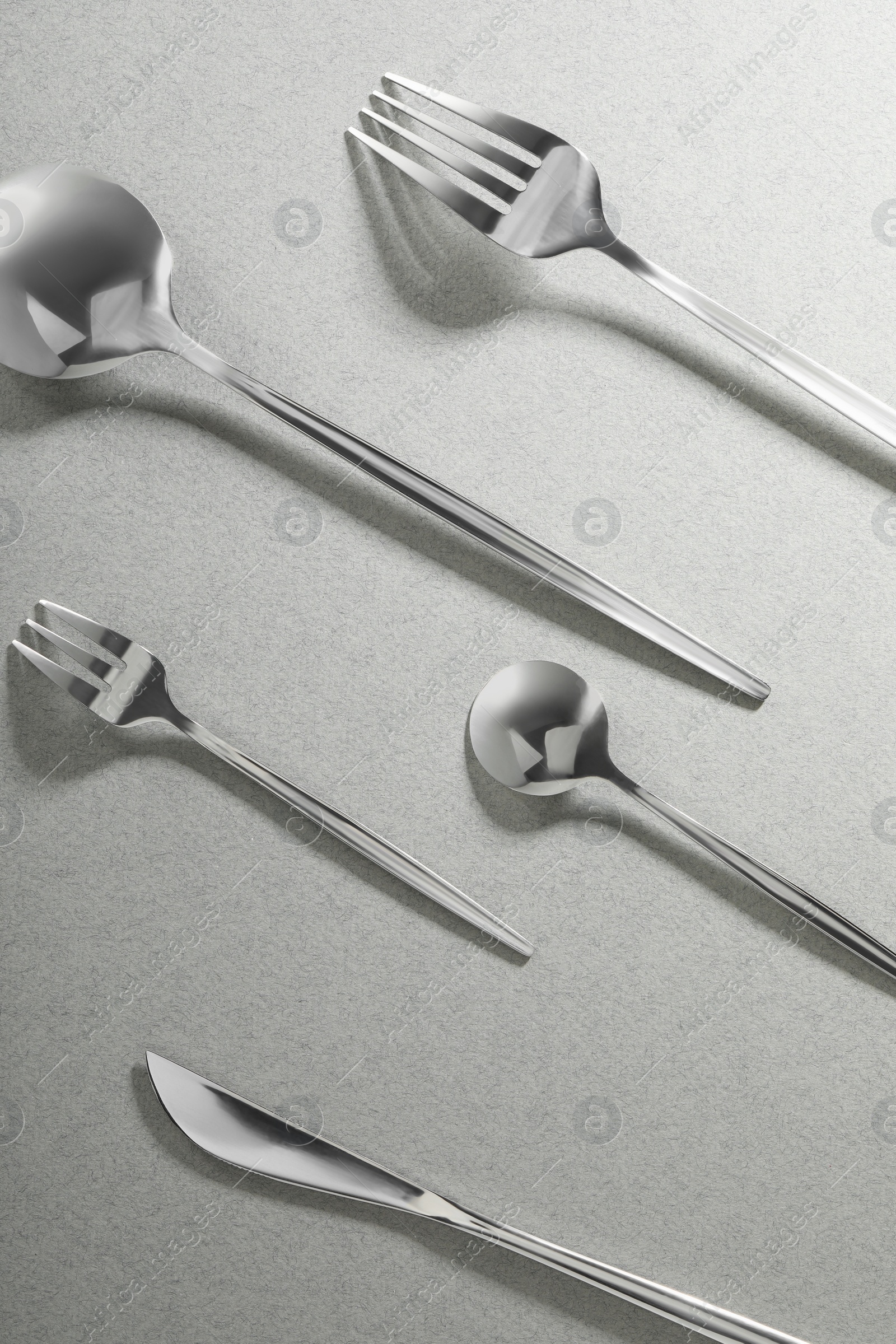 Photo of Forks, knife and spoons on grey background, flat lay. Stylish cutlery set