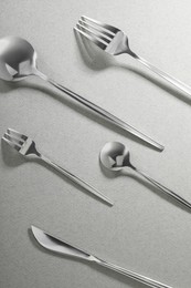 Photo of Forks, knife and spoons on grey background, flat lay. Stylish cutlery set