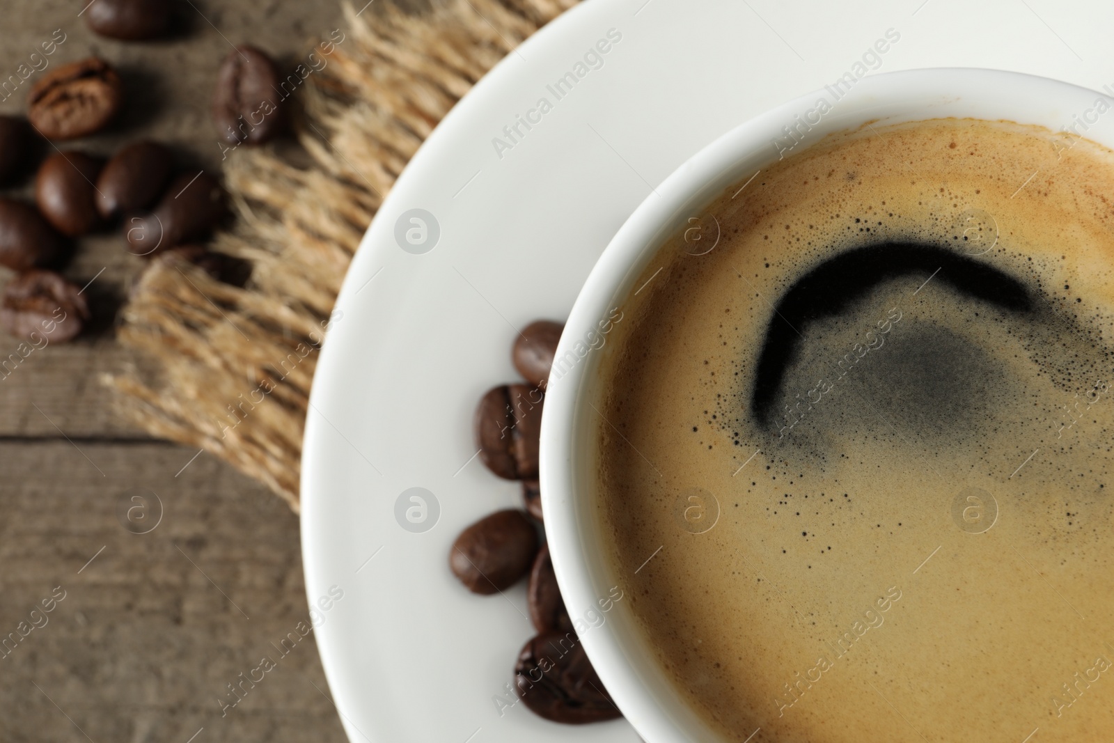 Photo of Cup of aromatic coffee on wooden table, top view. Space for text