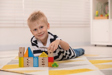 Photo of Cute little boy playing with wooden toys indoors, space for text