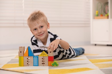 Cute little boy playing with wooden toys indoors, space for text