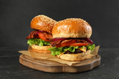 Photo of Tasty burgers on black wooden table. Fast food