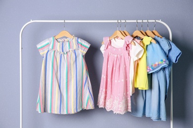 Rack with stylish child clothes on color background