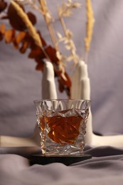 Photo of Glass of tasty alcohol drink and decor on grey fabric, selective focus
