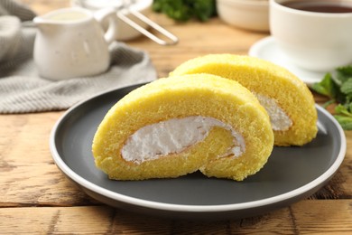 Delicious cake roll with cream filling on wooden table, closeup