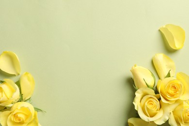 Beautiful yellow roses and petals on light olive background, flat lay. Space for text
