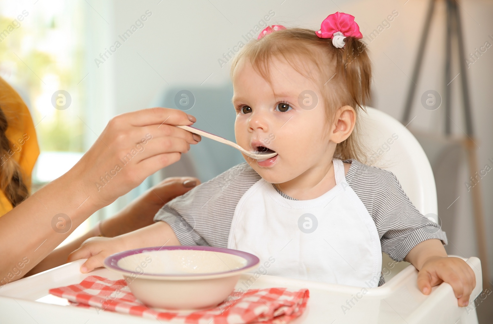 Photo of Mother feeding her cute little baby with healthy food at home