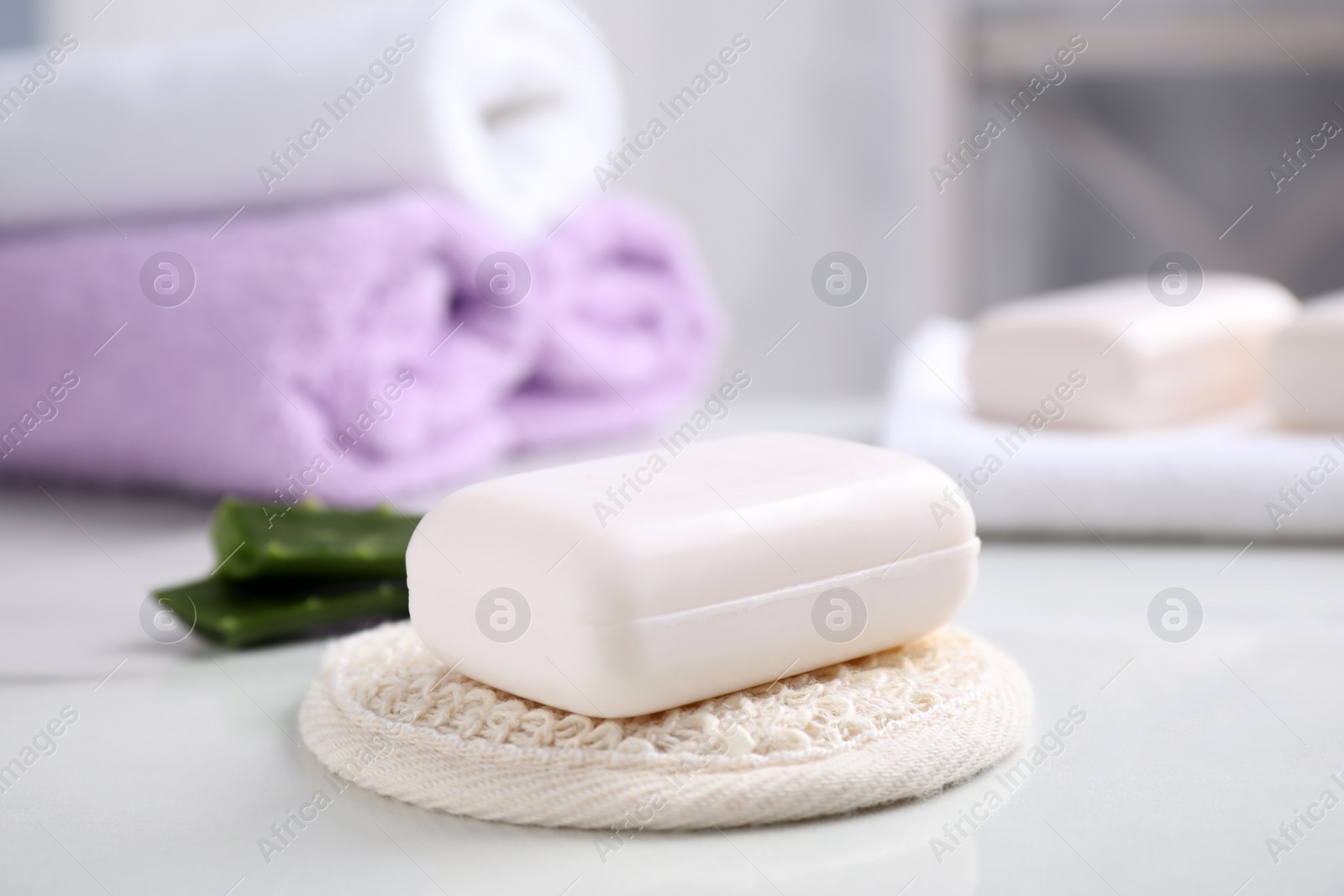 Photo of Soap bar and cloth on white table indoors