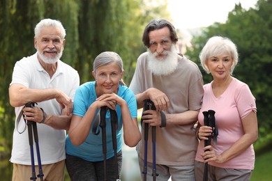 Photo of Group of senior people with Nordic walking poles outdoors