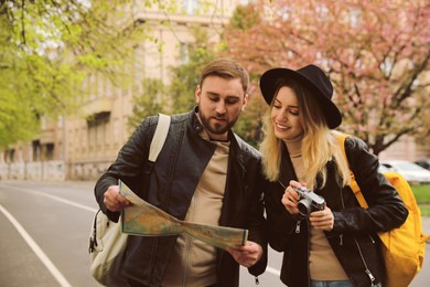 Couple of tourists with map and camera on city street