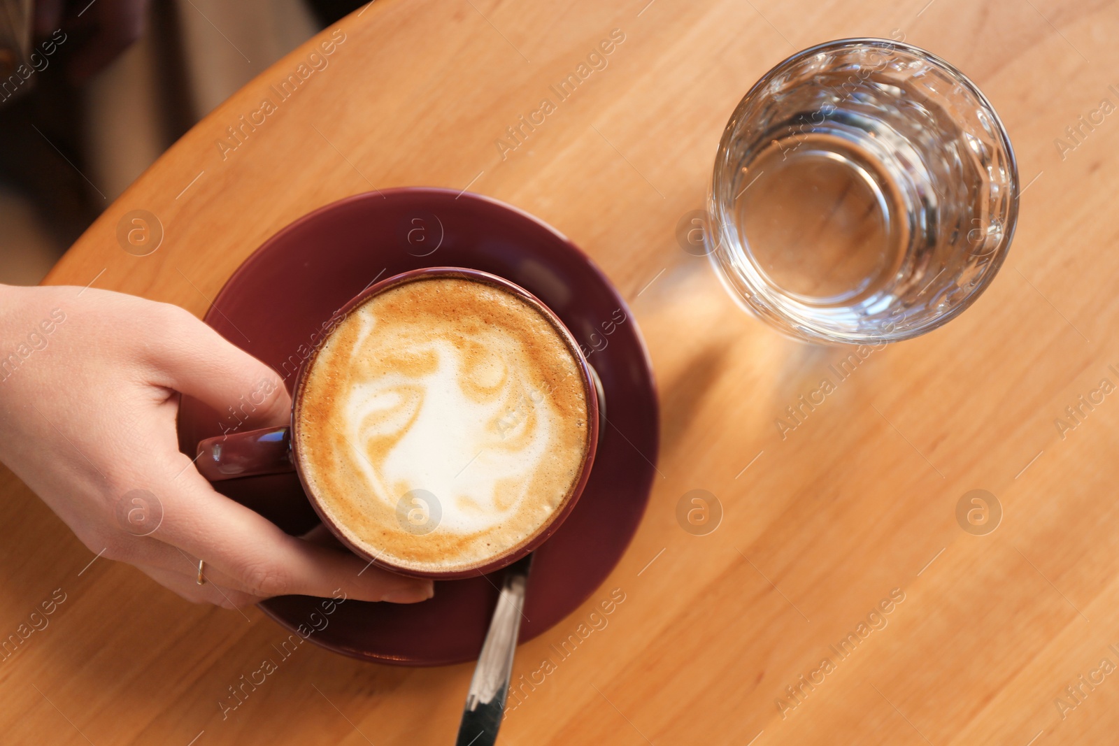 Photo of Woman with cup of aromatic coffee at table in cafe, top view