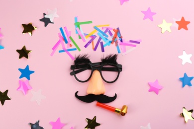 Photo of Clown face, confetti and party horn on pink background, flat lay