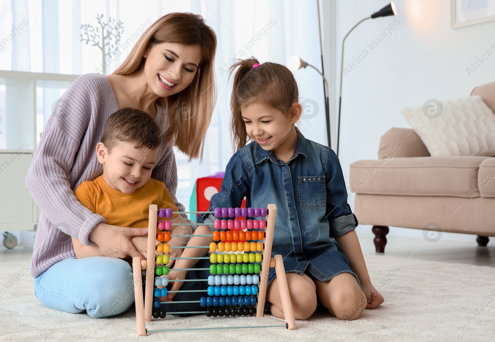 Photo of Nanny and little children playing with counting frame at home