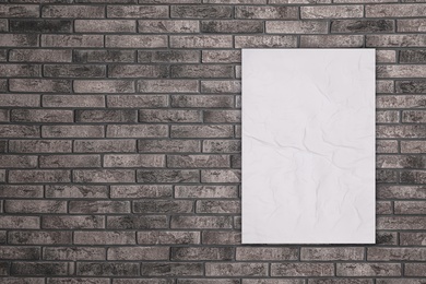 Image of Blank creased poster on grey brick wall. Mockup for design 