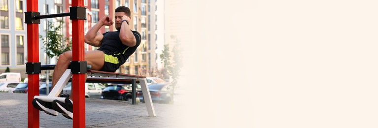 Handsome man doing abs exercise on bench at outdoor gym, space for text. Banner design