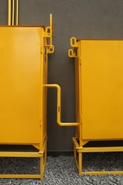 Photo of Yellow gas distribution cabinet near brown wall outdoors