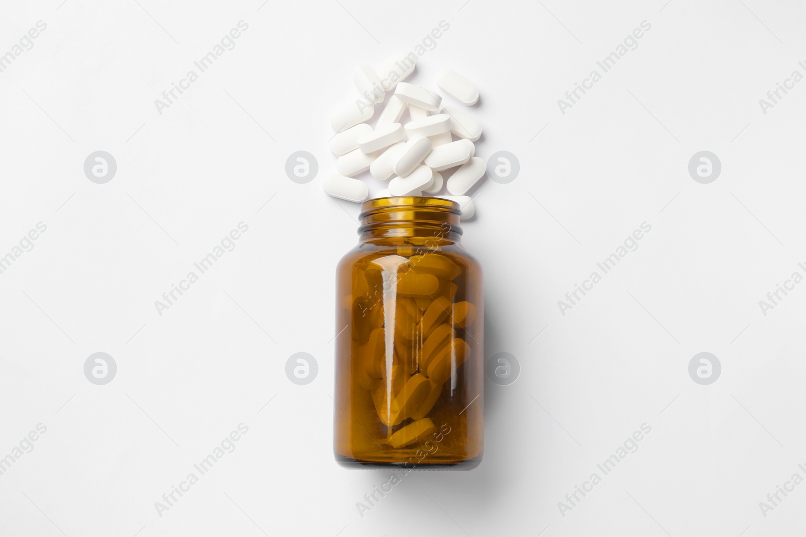 Photo of Vitamin pills and bottle on white background, top view