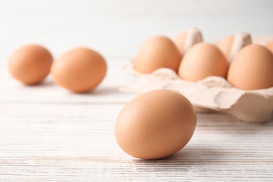 Photo of Raw brown chicken egg on wooden table, closeup