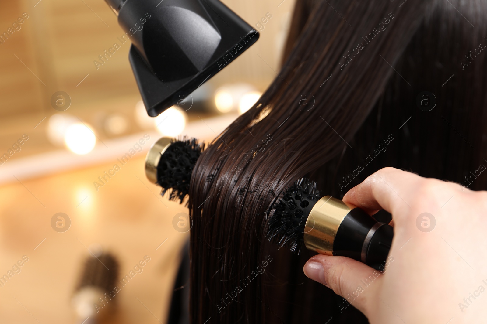 Photo of Hairdresser blow drying client's hair in salon, closeup