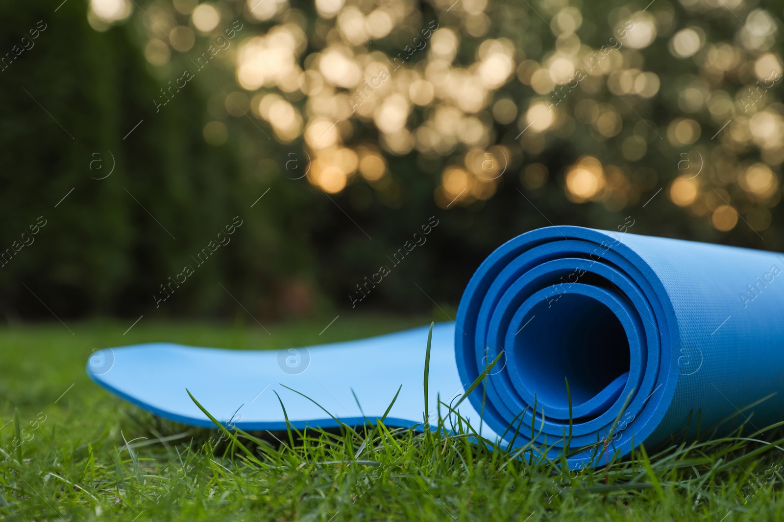 Photo of Blue karemat or fitness mat on green grass outdoors