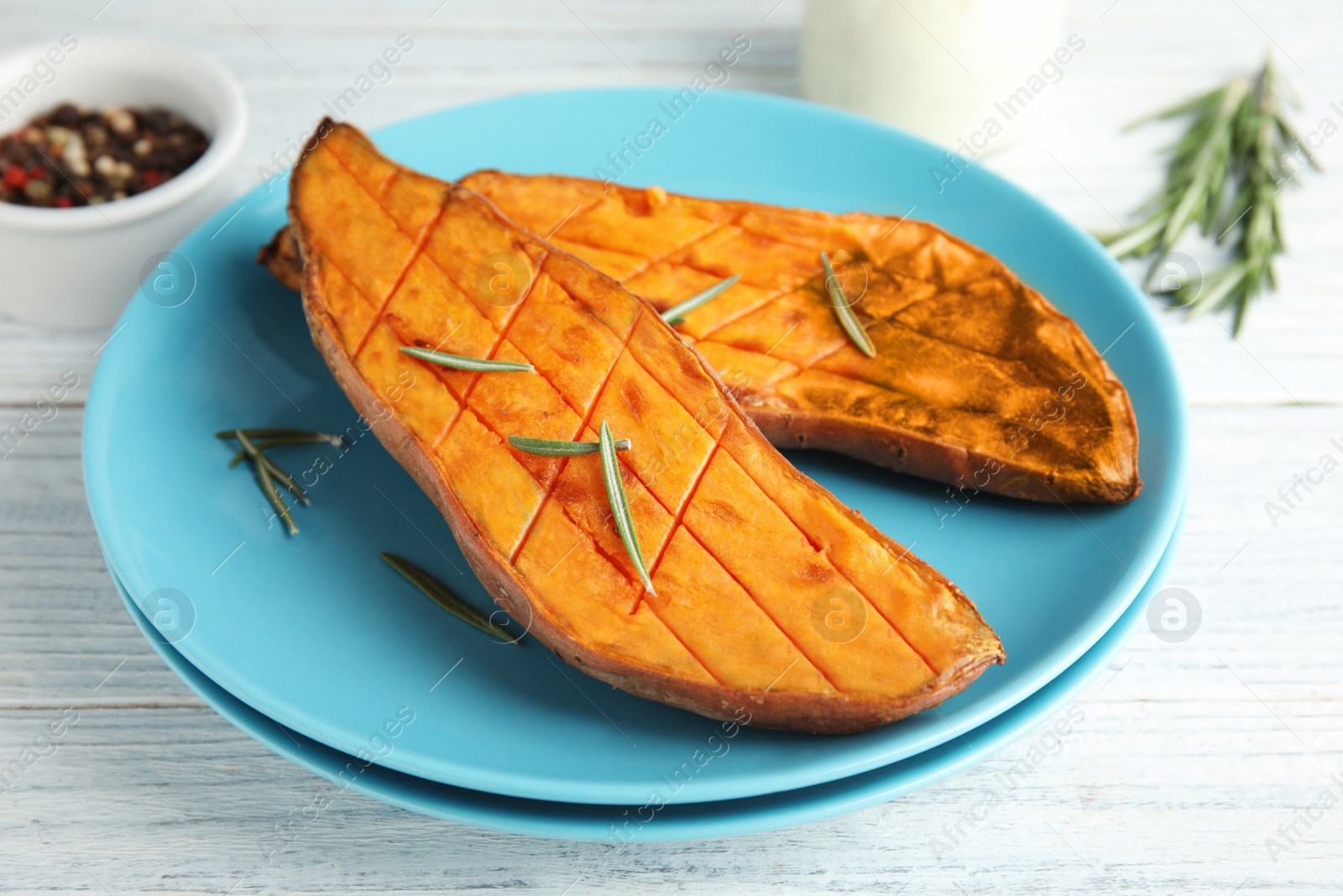 Photo of Plate with baked sweet potato on white wooden table, closeup