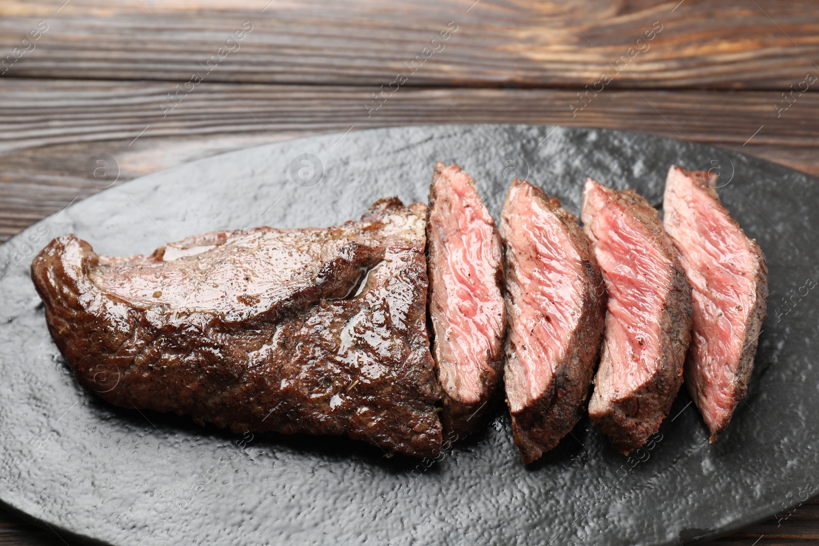 Photo of Pieces of delicious grilled beef meat on wooden table, closeup