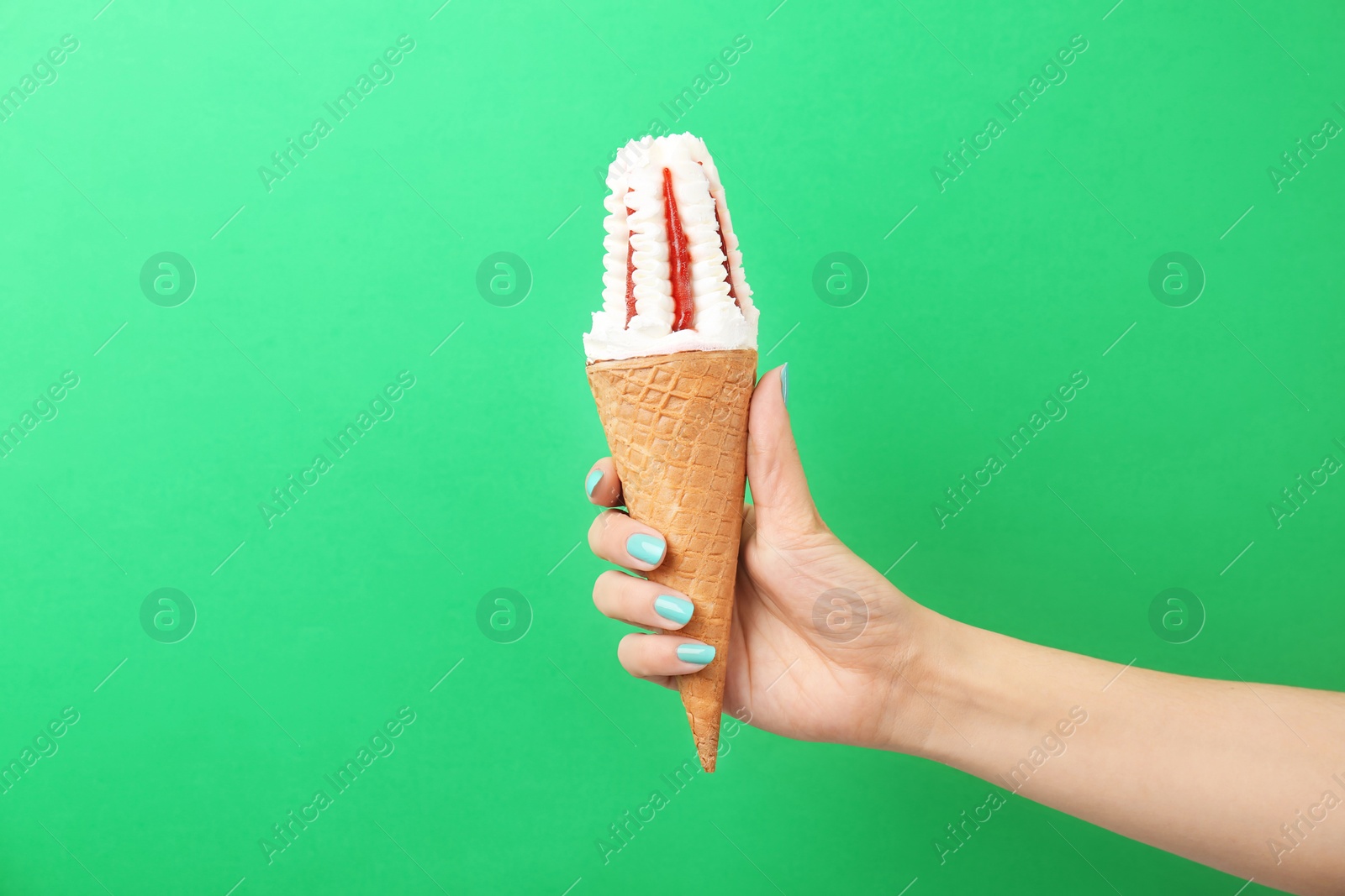 Photo of Woman holding yummy ice cream on color background. Focus on hand