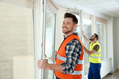 Construction workers installing plastic windows in house