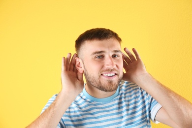 Photo of Young man with hearing problem on color background