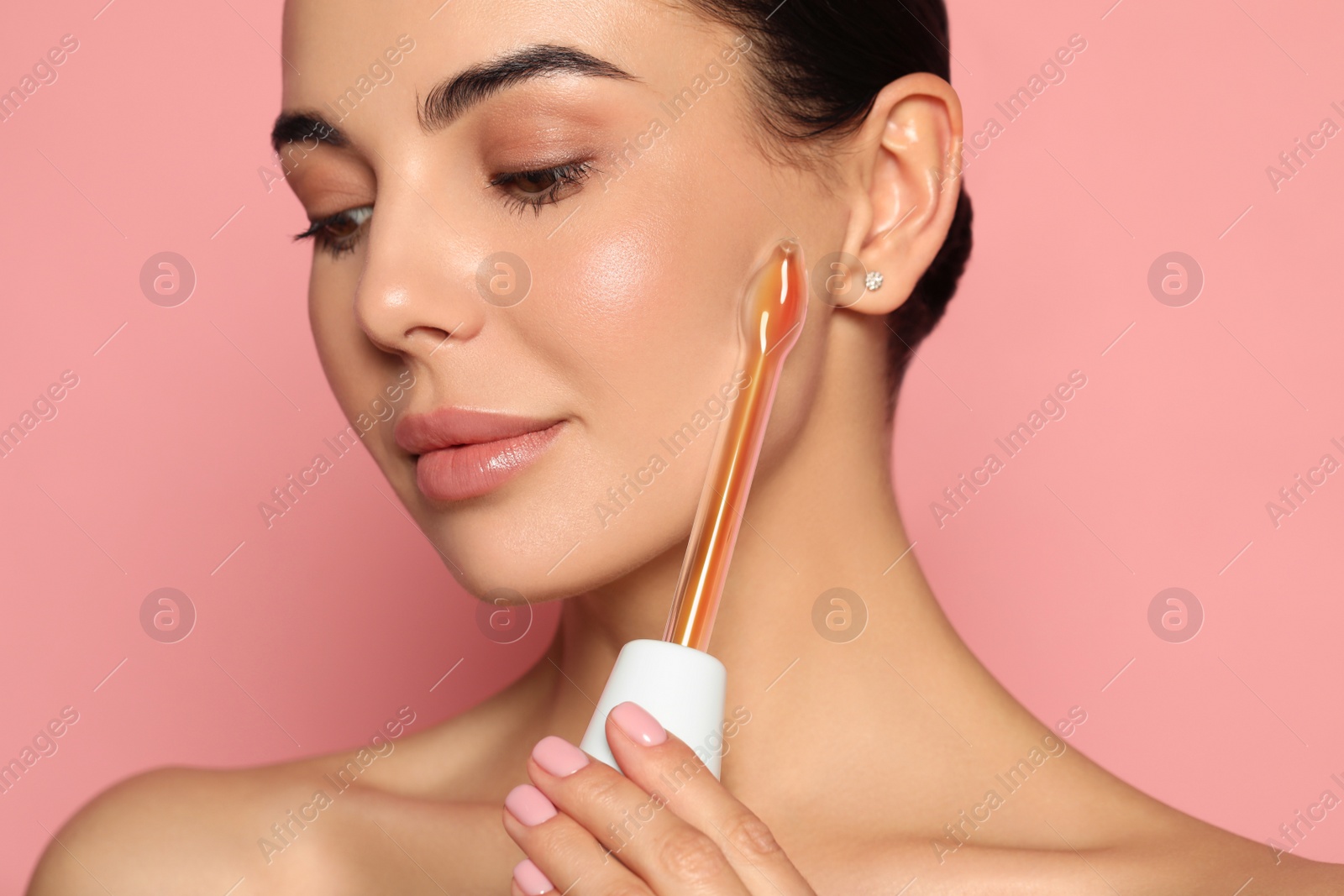 Photo of Woman using high frequency darsonval device on pink background, closeup