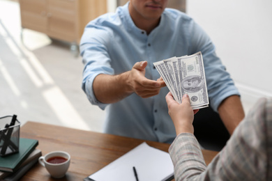 Photo of Woman giving bribe money to man at table, closeup