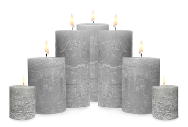 Set of burning grey candles on white background