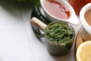 Photo of Different marinades on white tiled table, closeup. Space for text