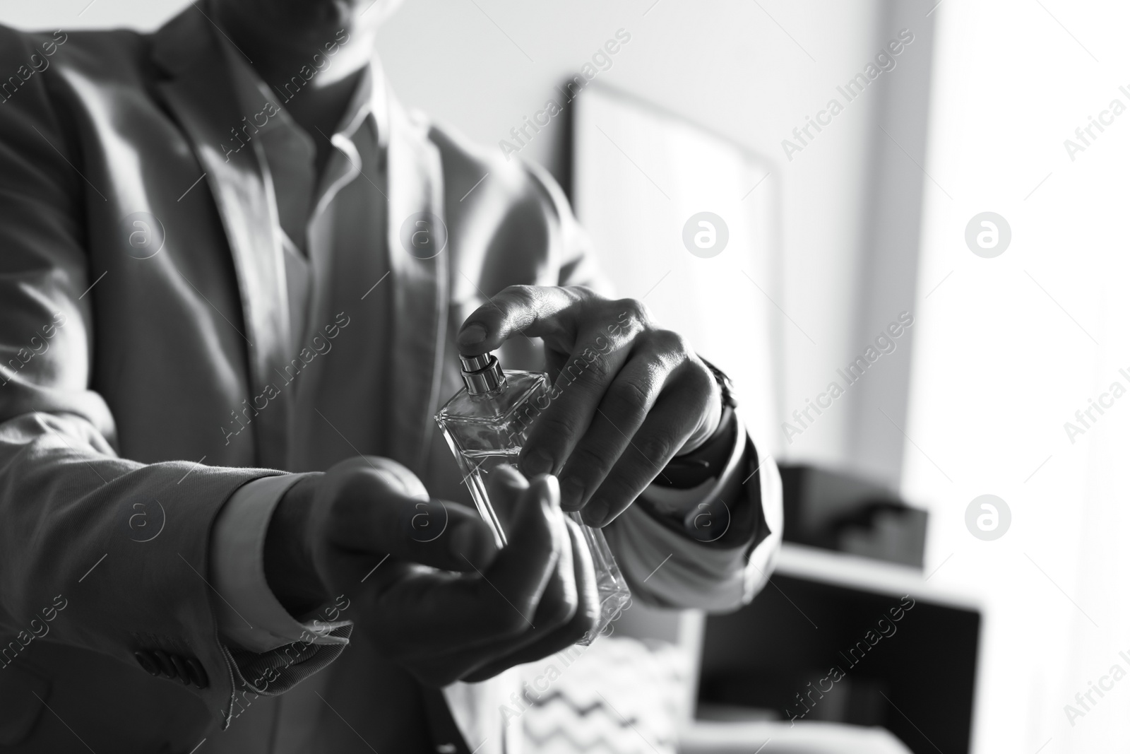 Photo of Man applying perfume on wrist indoors, closeup with space for text. Black and white effect