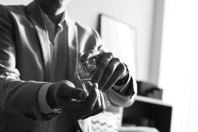 Man applying perfume on wrist indoors, closeup with space for text. Black and white effect