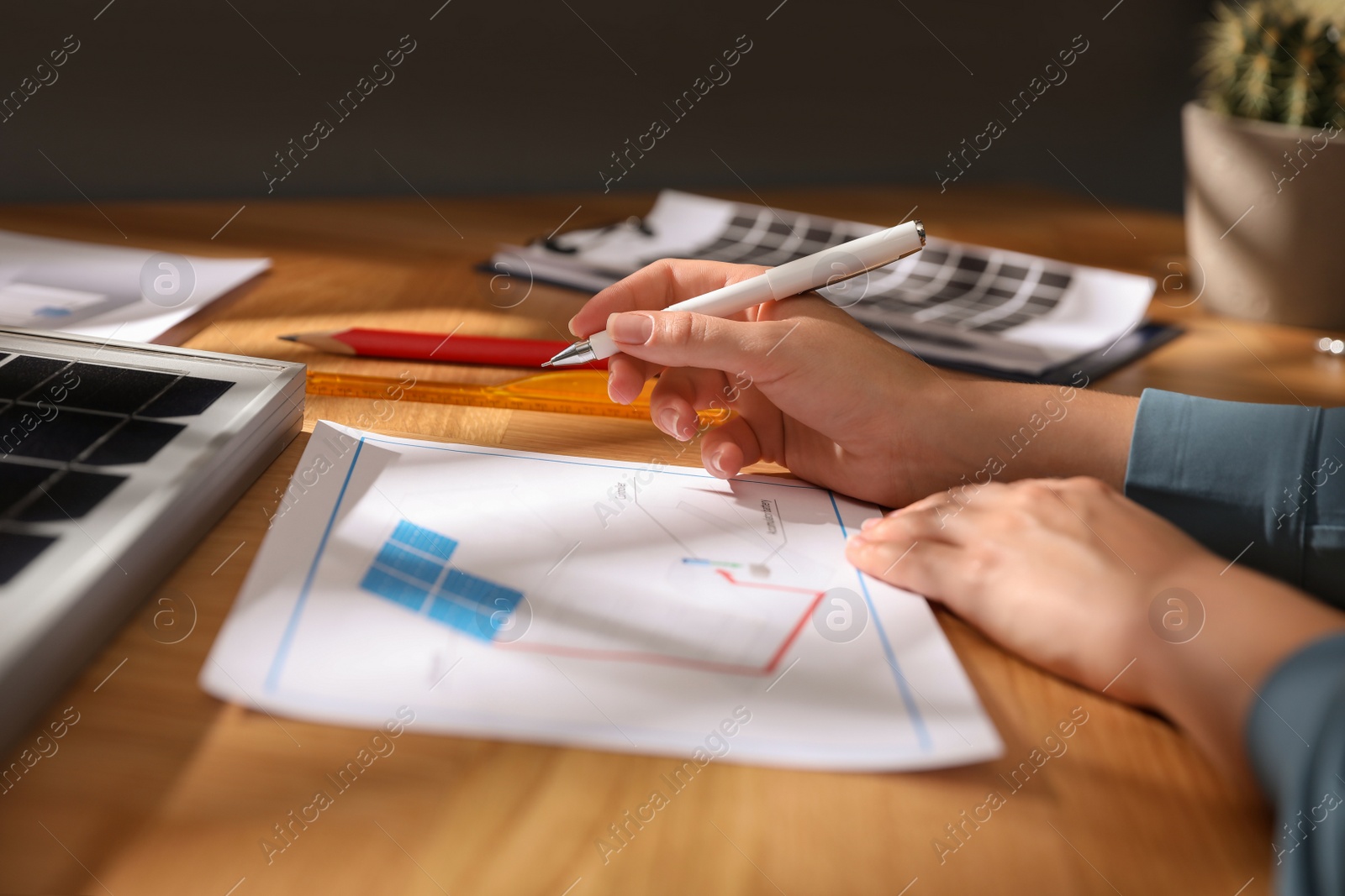 Photo of Woman working on house project with solar panels at table in office, closeup