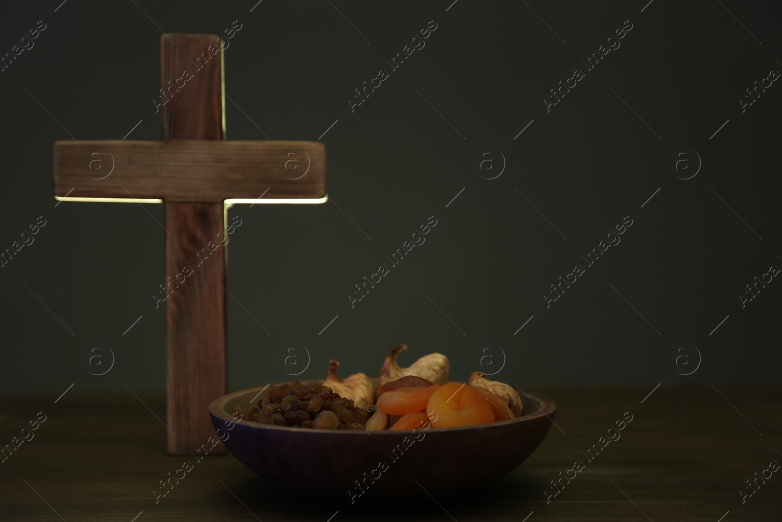 Photo of Cross and dried fruits on wooden table, space for text. Lent season