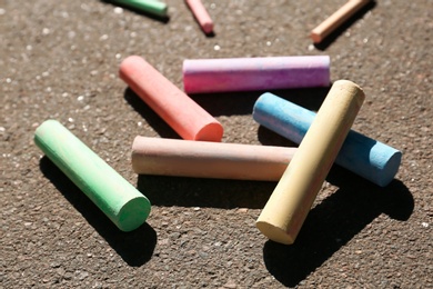 Photo of Many colorful chalk sticks on asphalt, closeup