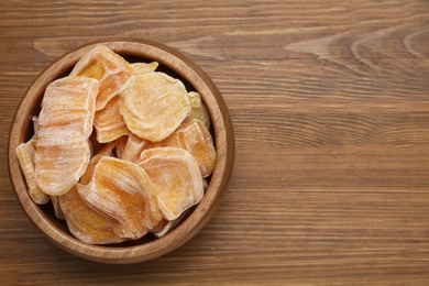 Delicious dried jackfruit slices in bowl on wooden table, top view. Space for text