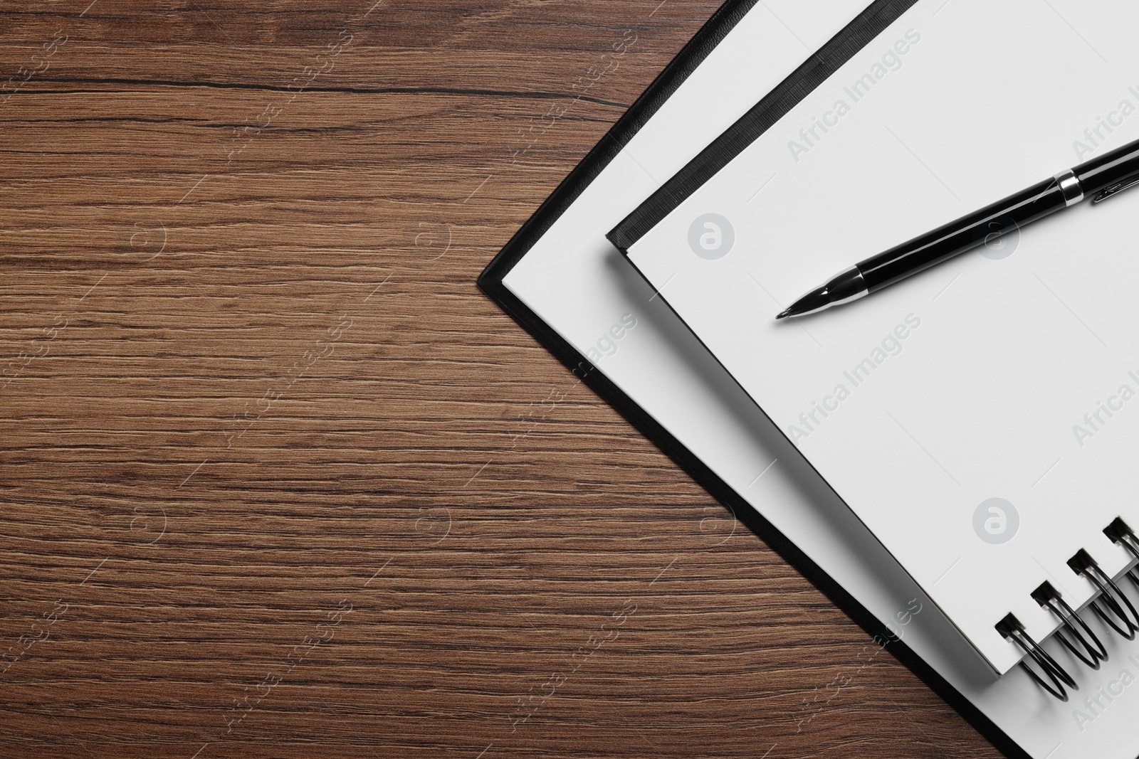 Photo of Ballpoint pen, notebook and clipboard with paper sheet on wooden table, flat lay. Space for text