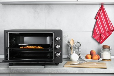Photo of Open electric oven with delicious pie on countertop in kitchen
