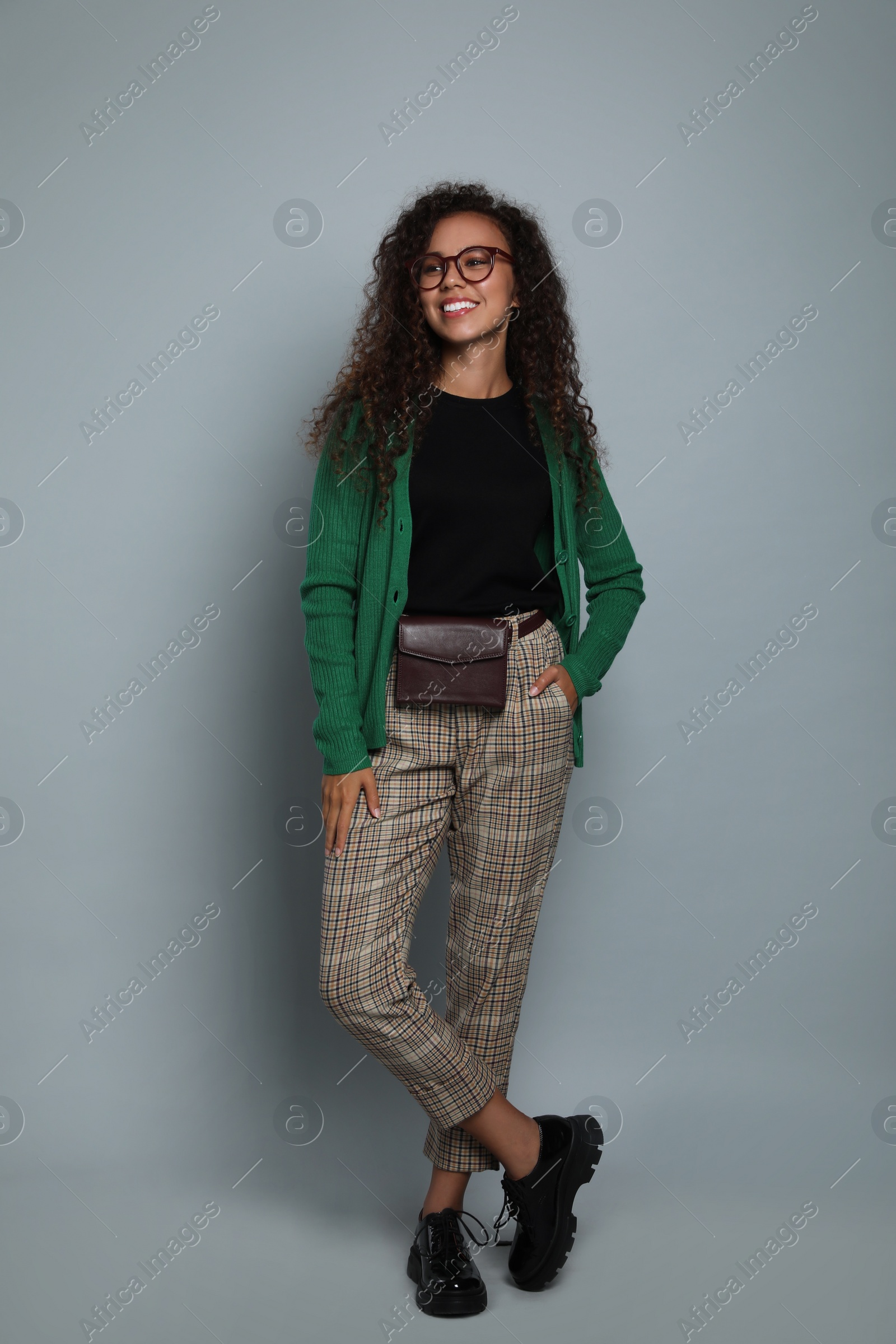 Photo of Beautiful African American woman with stylish waist bag on grey background