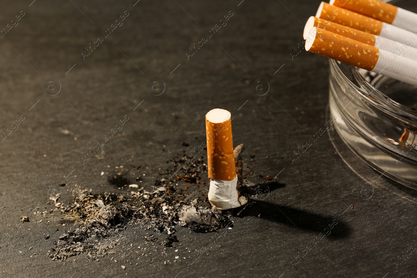 Photo of Ashtray and burnt cigarettes on black table, closeup. No smoking concept